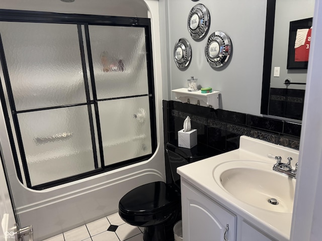 bathroom featuring vanity, toilet, enclosed tub / shower combo, and tile patterned floors