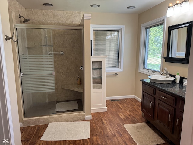 bathroom featuring wood finished floors, baseboards, a shower stall, and vanity