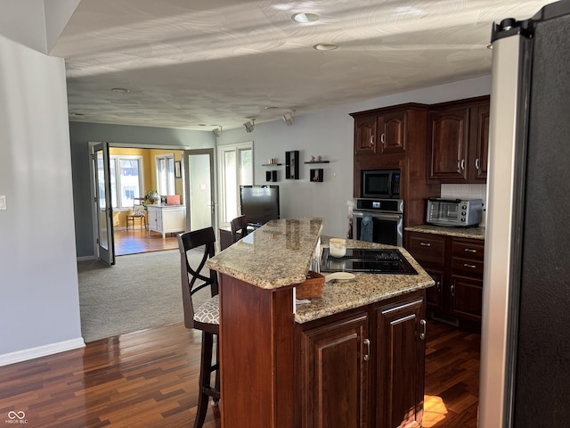 kitchen with stainless steel appliances, a kitchen breakfast bar, a kitchen island, and dark wood-style flooring