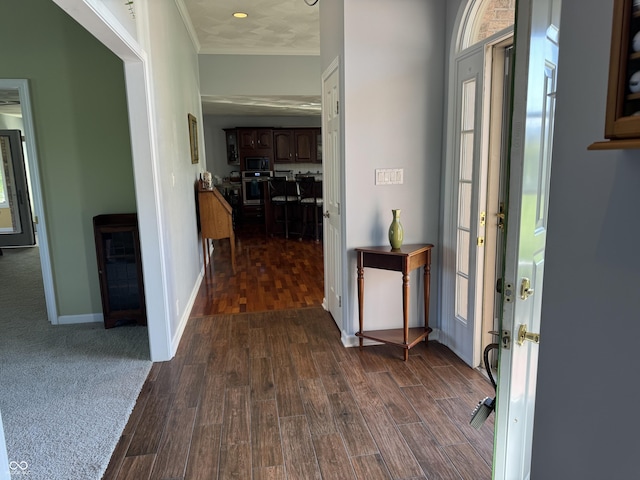 foyer entrance featuring dark wood-style floors, ornamental molding, and baseboards