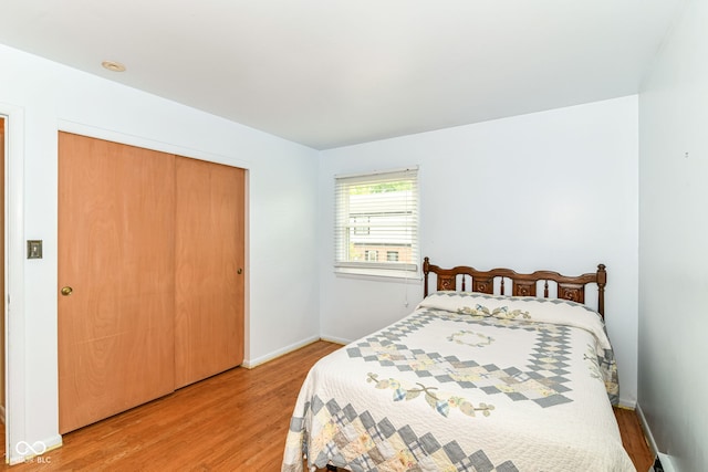 bedroom featuring wood finished floors, baseboards, and a closet
