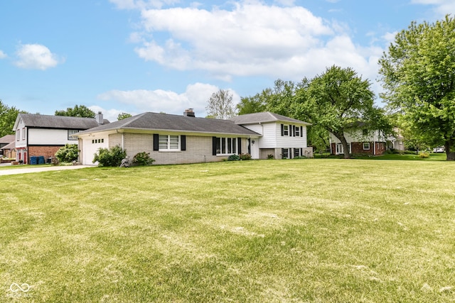 tri-level home with brick siding, a chimney, an attached garage, a front lawn, and driveway