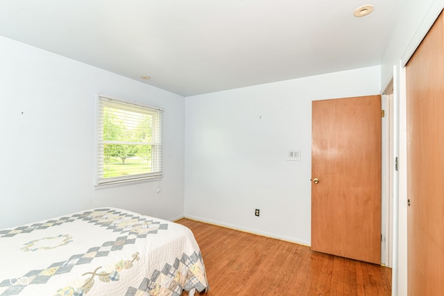 bedroom with light wood-type flooring, baseboards, and a closet