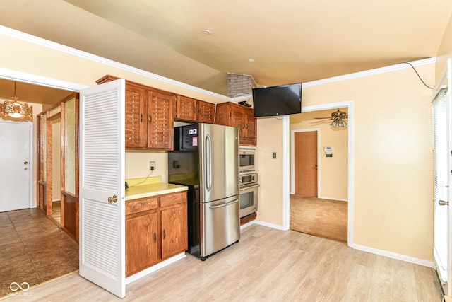 kitchen featuring appliances with stainless steel finishes, ceiling fan, brown cabinets, light countertops, and vaulted ceiling