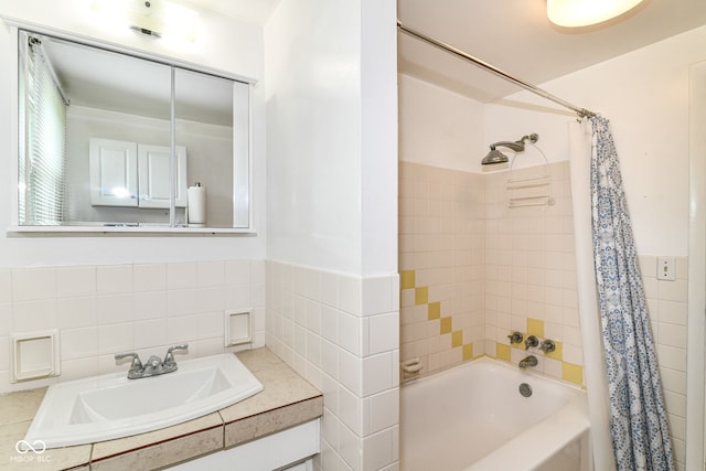 full bath with tile walls, a sink, shower / bath combination with curtain, and a wainscoted wall
