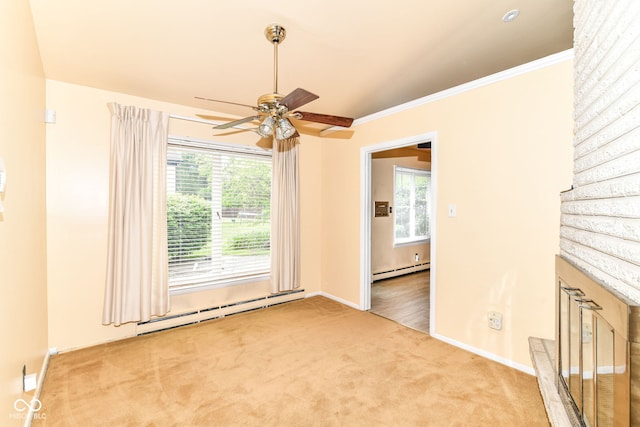 carpeted empty room with a baseboard radiator, a ceiling fan, baseboards, and crown molding