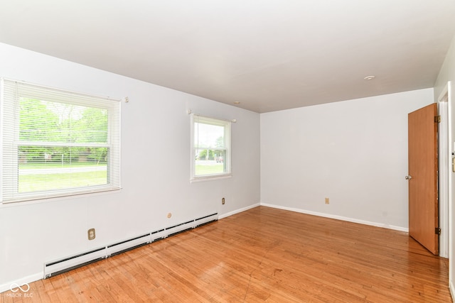 empty room with a baseboard radiator, light wood-type flooring, and baseboards