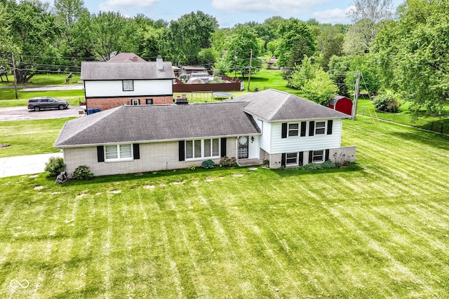 tri-level home with brick siding, a front lawn, roof with shingles, and a chimney