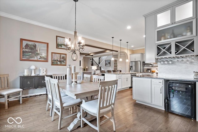 1013 Domino Dr, Carmel, IN 46032 - dining room featuring crown molding, wood finished floors, beverage cooler, a notable chandelier, and recessed lighting