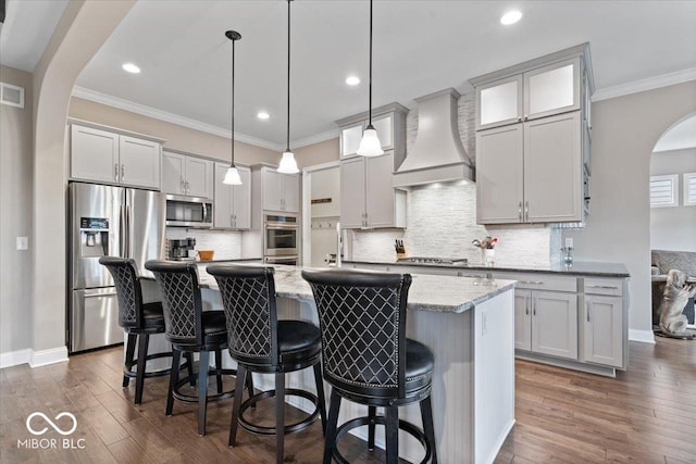 1013 Domino Dr, Carmel, IN 46032 - kitchen with appliances with stainless steel finishes, arched walkways, custom exhaust hood, a center island with sink, and dark wood-style floors
