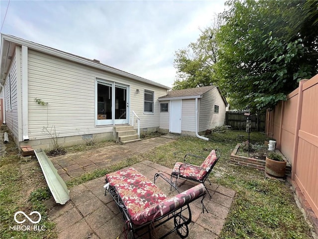 back of property with an outdoor structure, a patio, a fenced backyard, crawl space, and entry steps