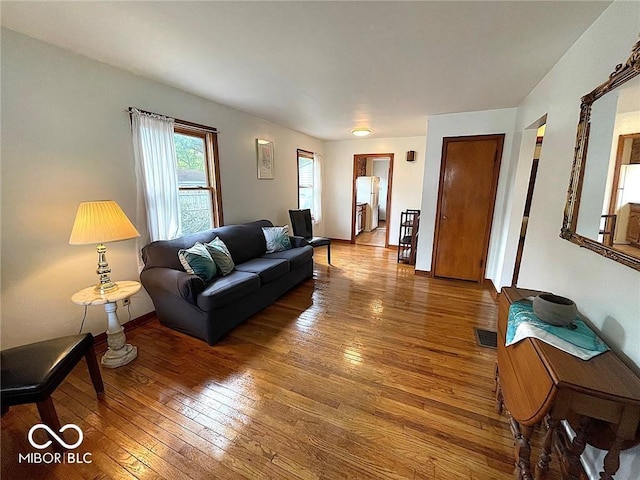 living room with wood-type flooring, baseboards, and visible vents