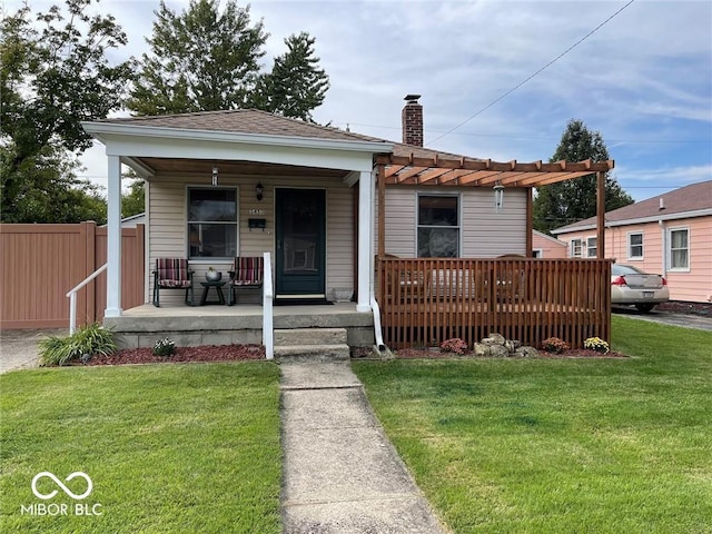 view of front facade featuring a porch, a front lawn, fence, and a chimney