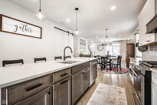 544 N Beville Ave, Indianapolis, IN 46201 - kitchen with appliances with stainless steel finishes, a sink, a barn door, recessed lighting, and light wood-style floors