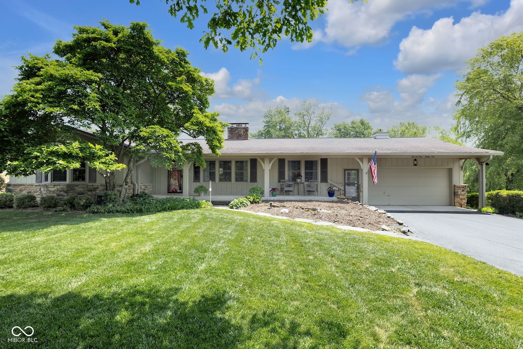 7135 Lantern Rd, Indianapolis, IN 46256 - ranch-style home with stone siding, a chimney, a front yard, an attached garage, and asphalt driveway