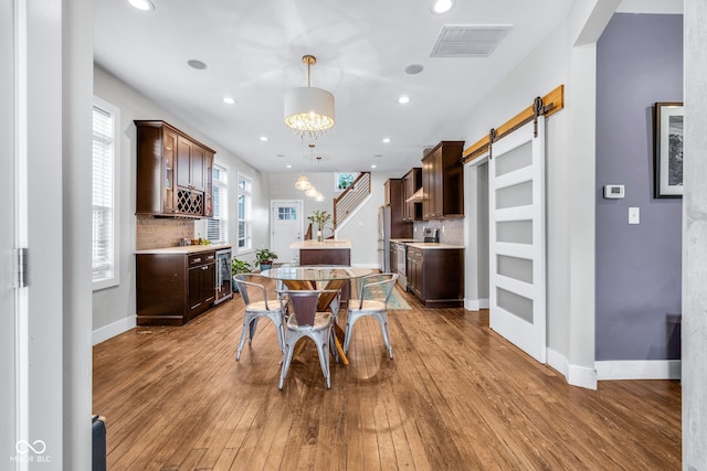 715 Terrace Ave, Indianapolis, IN 46203 - dining space featuring wood-type flooring, recessed lighting, a barn door, and a dry bar