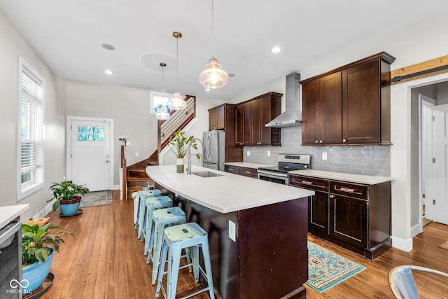 715 Terrace Ave, Indianapolis, IN 46203 - kitchen with wall chimney exhaust hood, stainless steel appliances, decorative backsplash, dark brown cabinets, and wood finished floors