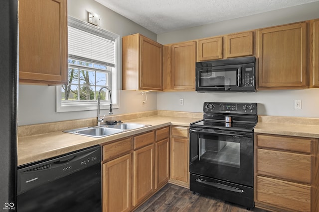 kitchen featuring dark wood-style flooring, a textured ceiling, a sink, light countertops, and black appliances