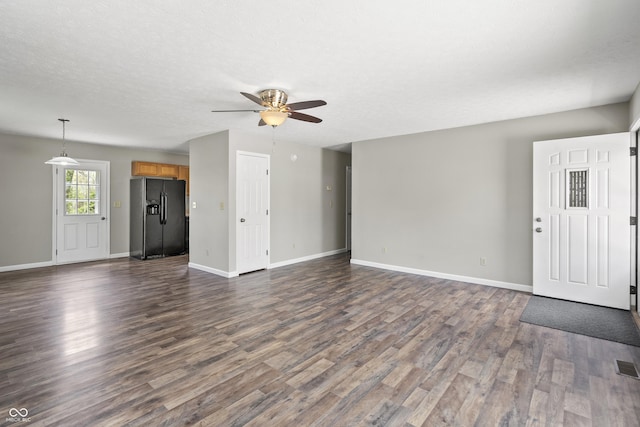 unfurnished living room with ceiling fan, dark wood finished floors, and baseboards