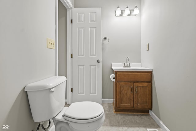 half bathroom featuring baseboards, vanity, and toilet