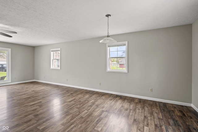 spare room featuring plenty of natural light, ceiling fan, and dark wood-type flooring