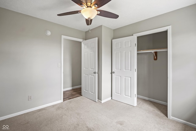 unfurnished bedroom featuring baseboards, light colored carpet, ceiling fan, and a closet
