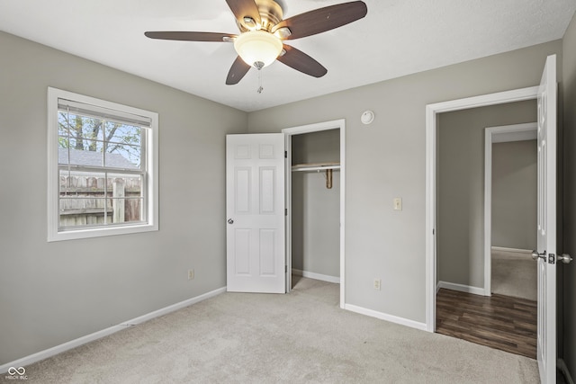 unfurnished bedroom with carpet floors, baseboards, ceiling fan, and a closet