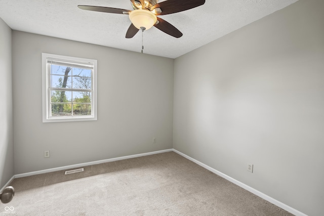 spare room featuring ceiling fan, a textured ceiling, carpet, baseboards, and visible vents