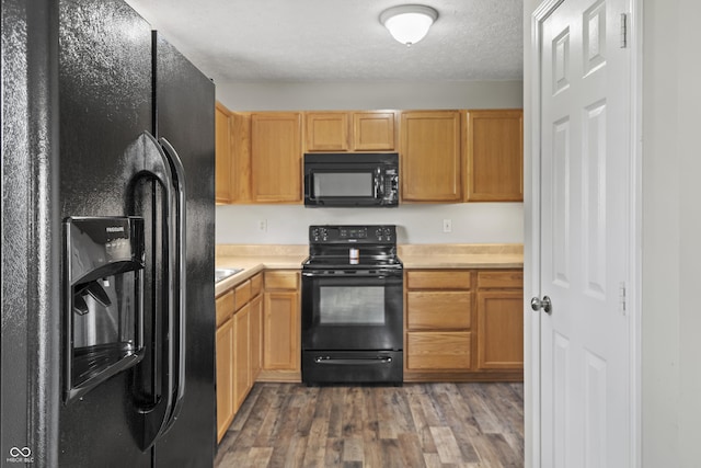 kitchen featuring light countertops, a textured ceiling, black appliances, and wood finished floors