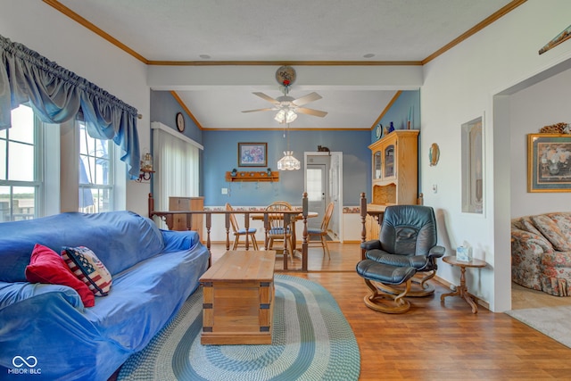 living room featuring baseboards, ornamental molding, a ceiling fan, and wood finished floors