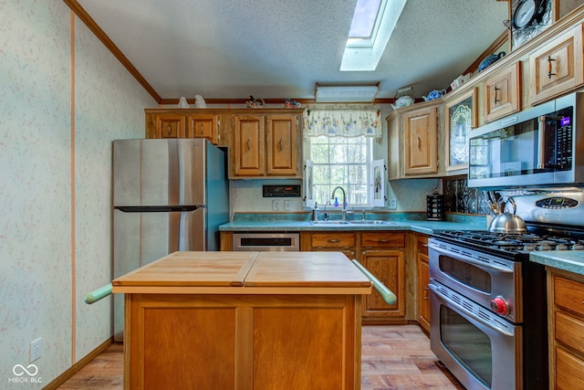 kitchen featuring appliances with stainless steel finishes, a sink, wood counters, a center island, and light wood-type flooring