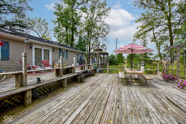 wooden terrace featuring a gazebo and outdoor dining area