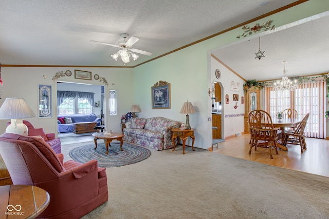 carpeted living area with a textured ceiling, ornamental molding, baseboards, and ceiling fan with notable chandelier