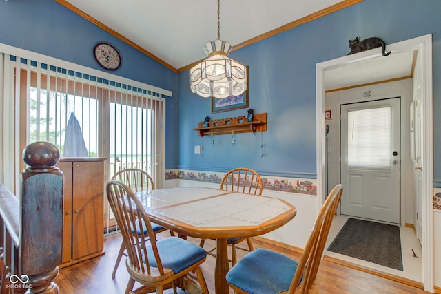 dining room with crown molding, wood finished floors, and vaulted ceiling