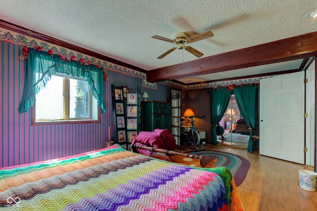 bedroom with beam ceiling, a ceiling fan, a textured ceiling, and wood finished floors