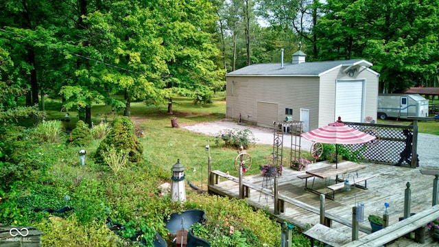 view of yard featuring a storage unit, a garage, an outbuilding, and a deck
