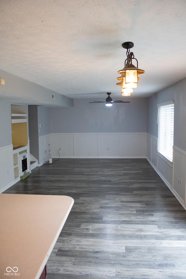 8912 Hosta Way, Indianapolis, IN 46113 - spare room featuring a textured ceiling, wood finished floors, a ceiling fan, wainscoting, and a fireplace