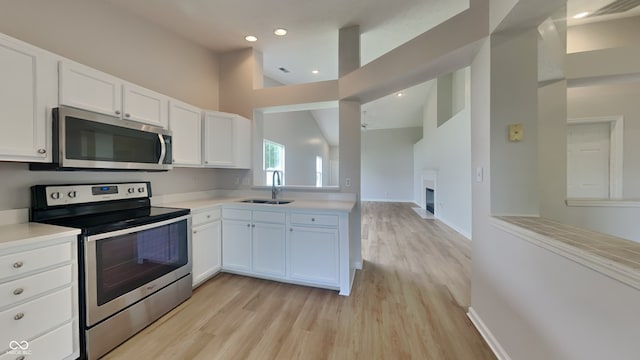 kitchen with light countertops, stainless steel appliances, a sink, and light wood finished floors