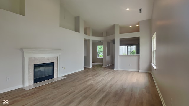 unfurnished living room with visible vents, a fireplace, wood finished floors, baseboards, and recessed lighting
