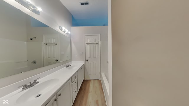 bathroom with visible vents, a sink, wood finished floors, and double vanity