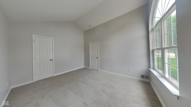 unfurnished room with high vaulted ceiling, baseboards, carpet, and visible vents