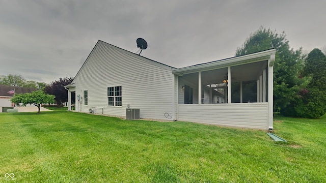 back of property with a lawn, central AC, a ceiling fan, and a sunroom