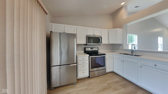 kitchen featuring light countertops, white cabinets, a sink, light wood-style flooring, and appliances with stainless steel finishes