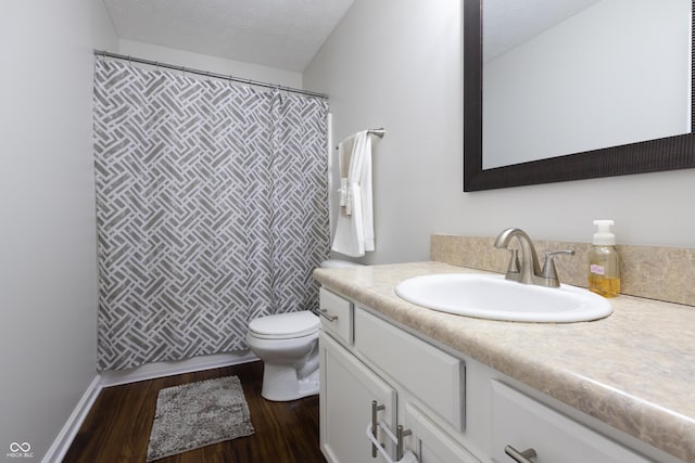 full bath featuring toilet, wood finished floors, vanity, a textured ceiling, and a shower with shower curtain