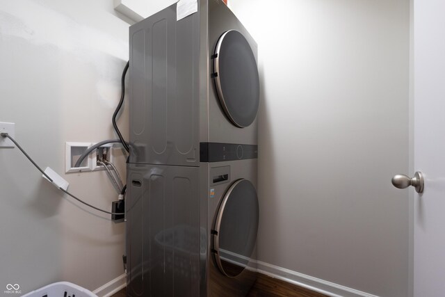 laundry room with laundry area, stacked washer / drying machine, baseboards, and dark wood finished floors