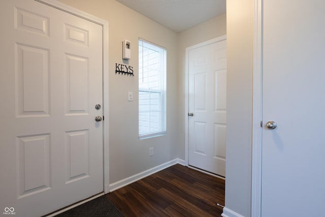 foyer featuring dark wood finished floors, baseboards, and a textured ceiling