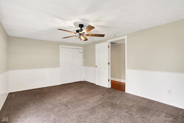 unfurnished bedroom with dark carpet, a closet, ceiling fan, and baseboards