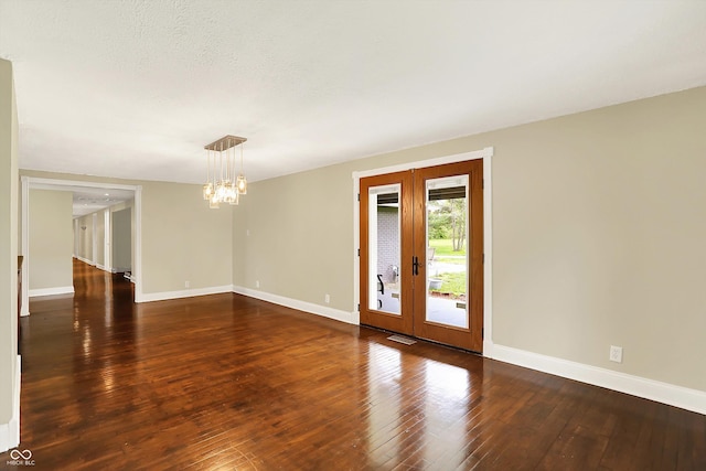 empty room featuring a chandelier, french doors, baseboards, and hardwood / wood-style flooring