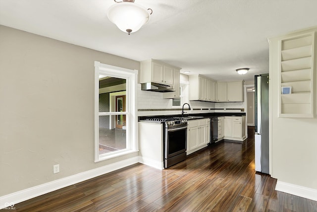 kitchen with stainless steel appliances, dark wood finished floors, under cabinet range hood, baseboards, and dark countertops