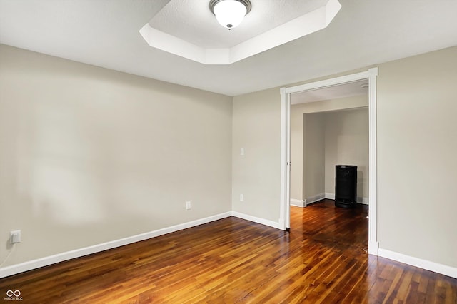 spare room featuring hardwood / wood-style flooring, baseboards, and a raised ceiling